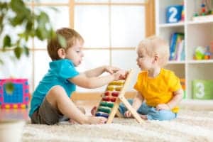 infant and toddler playing with abacus